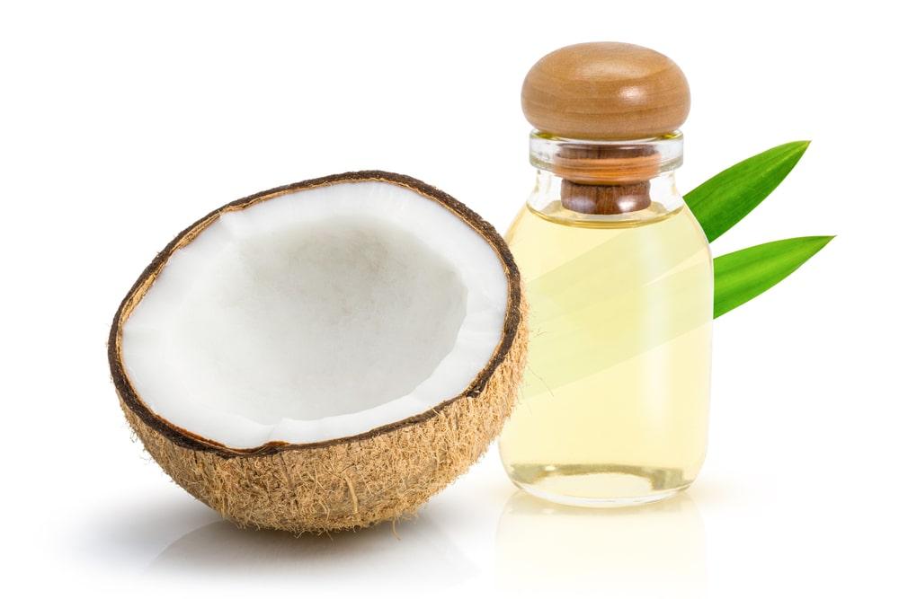 A Coconut Half Next to a Bottle of Coconut Oil
