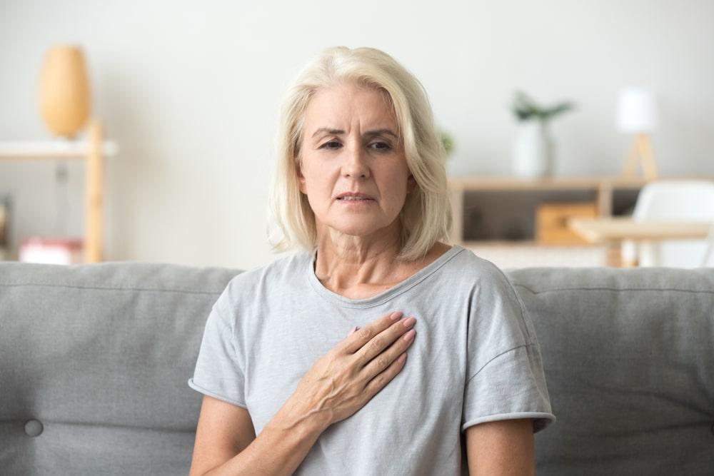 A woman holding her heart from pain