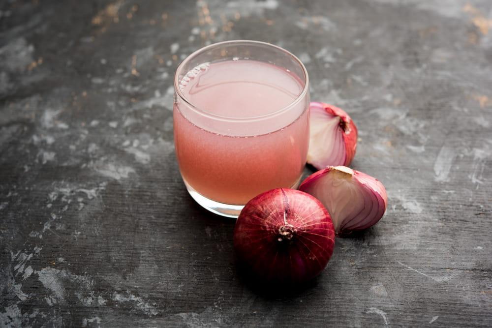 A Glass of Onion Juice Next to Red Onions