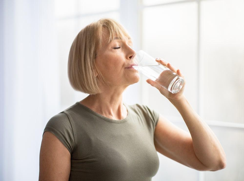 a woman drinking water to stay hydrated