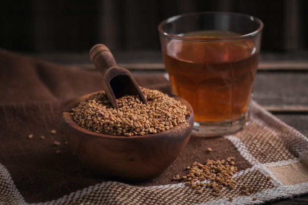 A Bowl of Fenugreek Next to a Glass of Liquid 