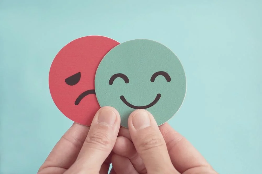 Hands Holding Happy and Angry Face Paper