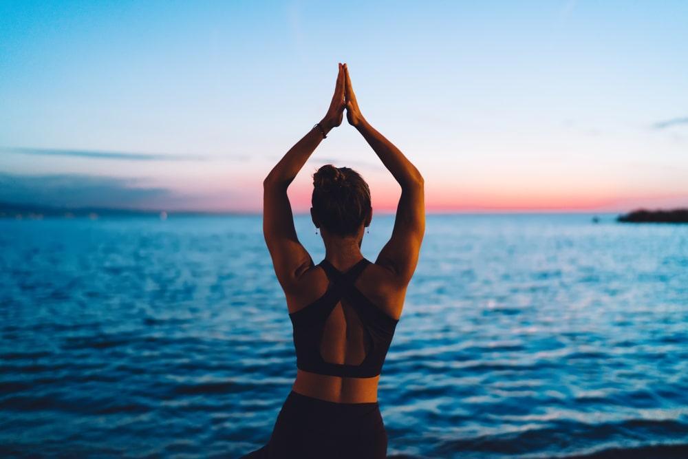 a woman doing yoga in front of the sea