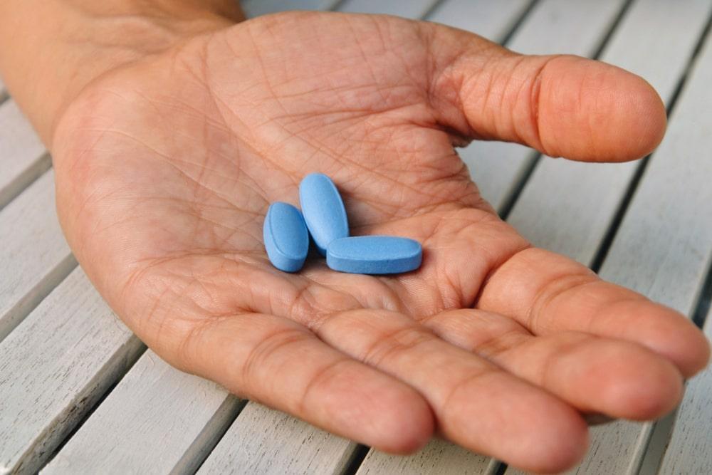 a person holding blue pills in his hand