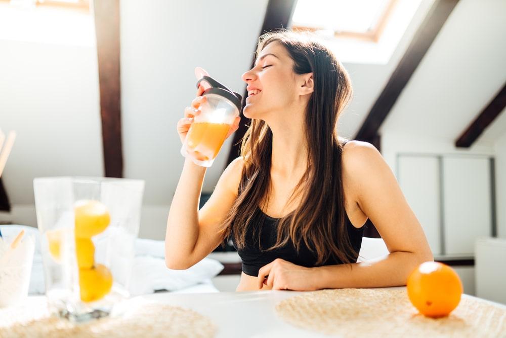 a happy woman drinking fresh orange juice