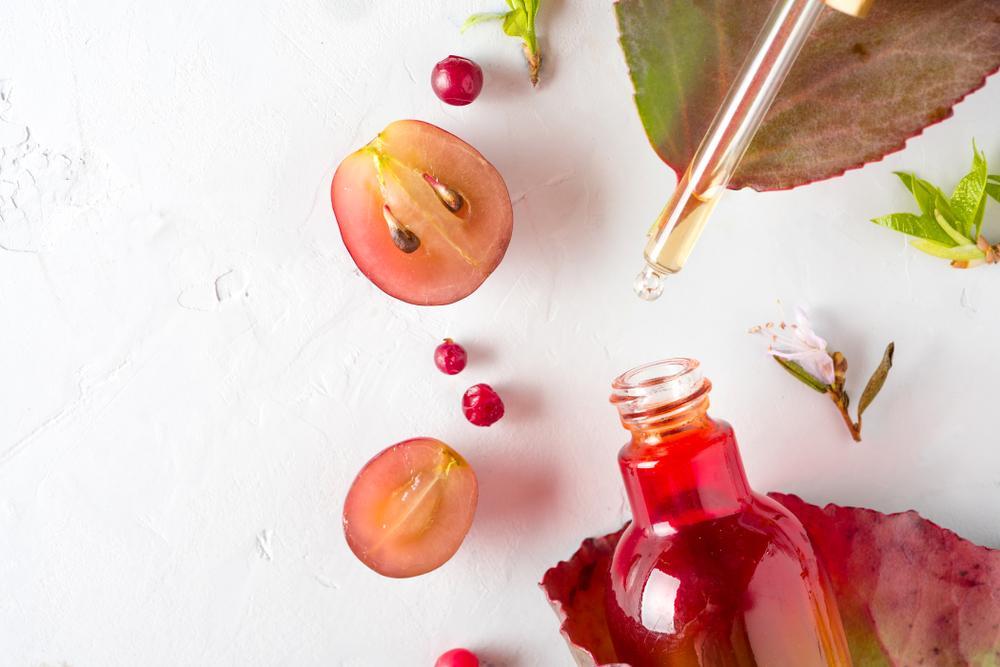 A Bottle of Cranberry Extract Next to a Grape 