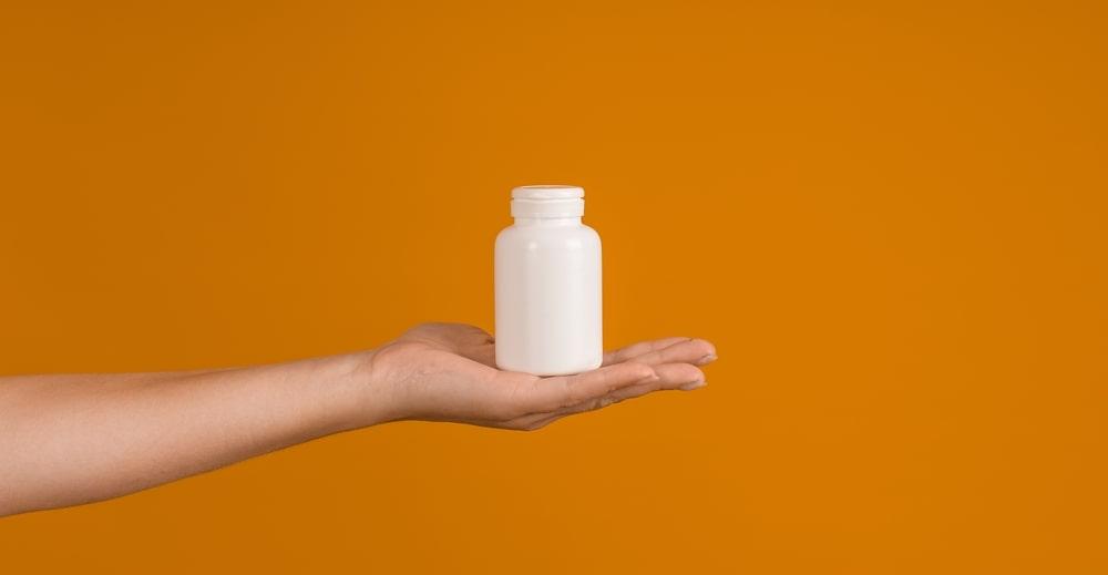 A Hand Holding a Bottle With L-Arginine