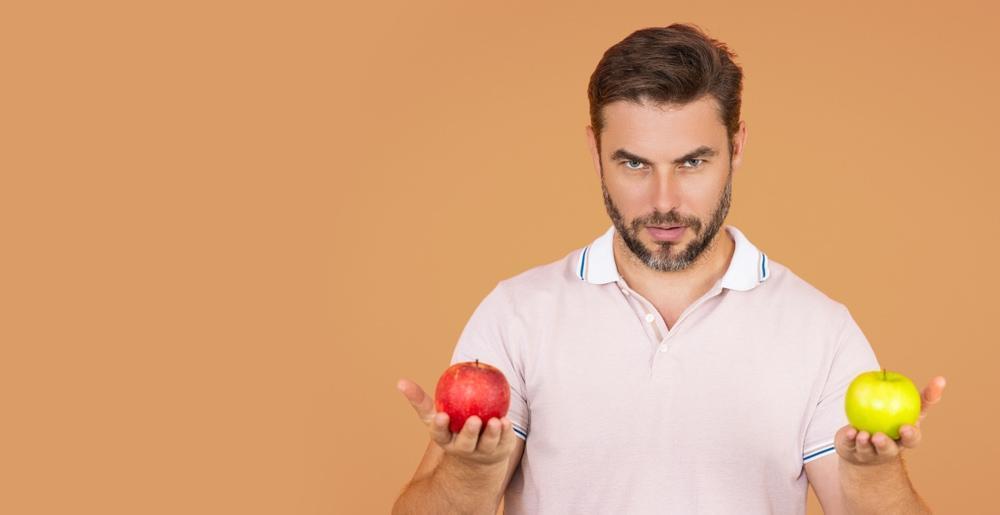 A Man Holding a Green and a Red Apple