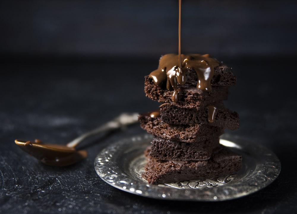 A Stack of Brownies With Dark Chocolate Being Poured From the Top