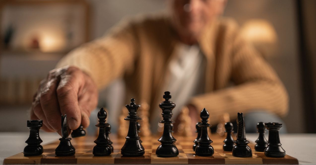 close-up of an elderly man playing chess, chessboard with pieces in the foreground