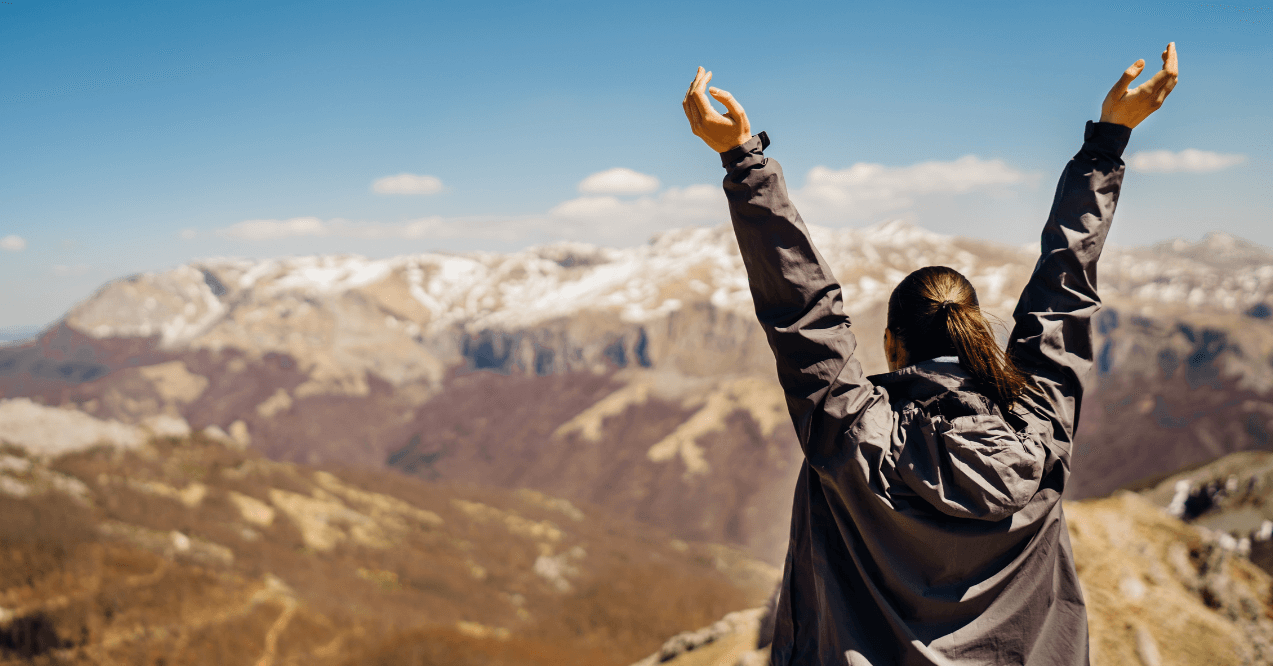 Woman on the mountain happy raising her hands