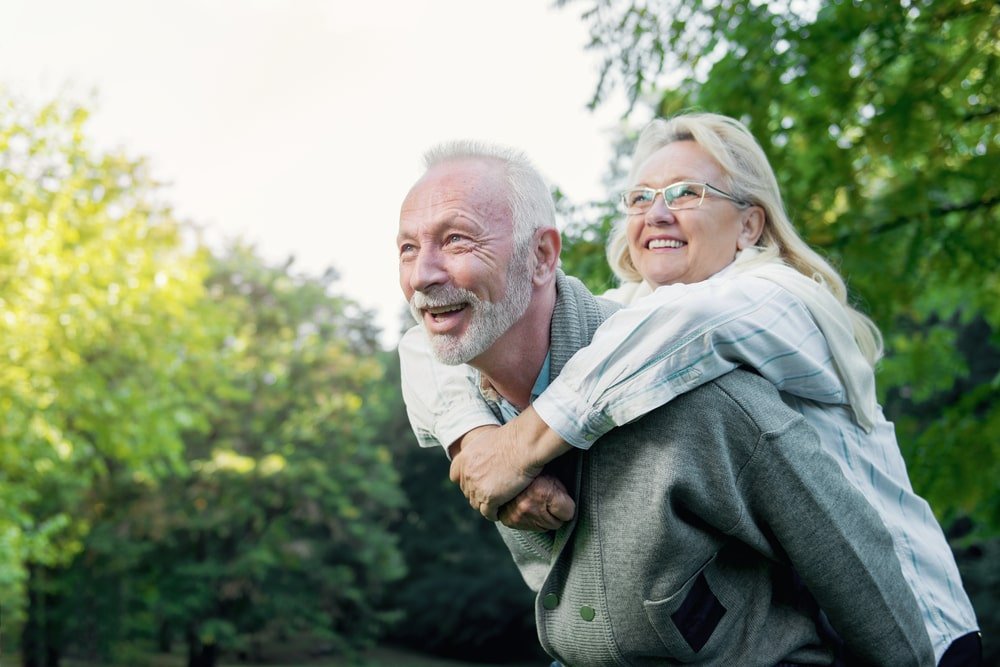 Happy Senior Couple Smiling Outdoors in Nature After Learning About the Best Longevity Supplements