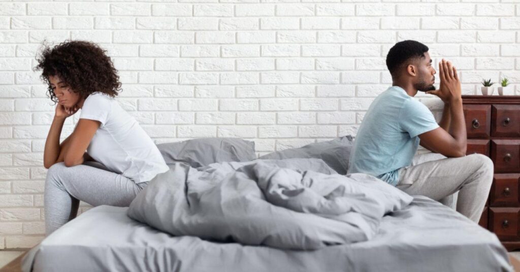 African-American Couple Sitting Apart Back to Back on Bed During Conflict