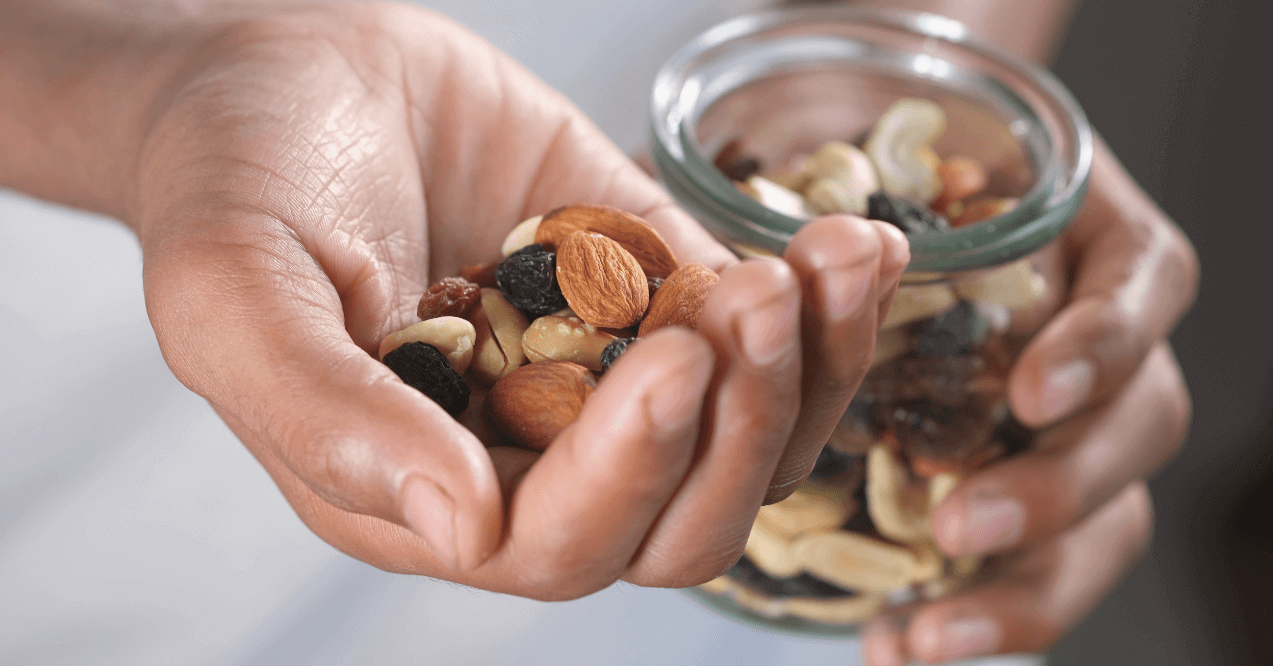 Mans Hand Holding A Variety of Nuts and a Glass Jar with Nuts