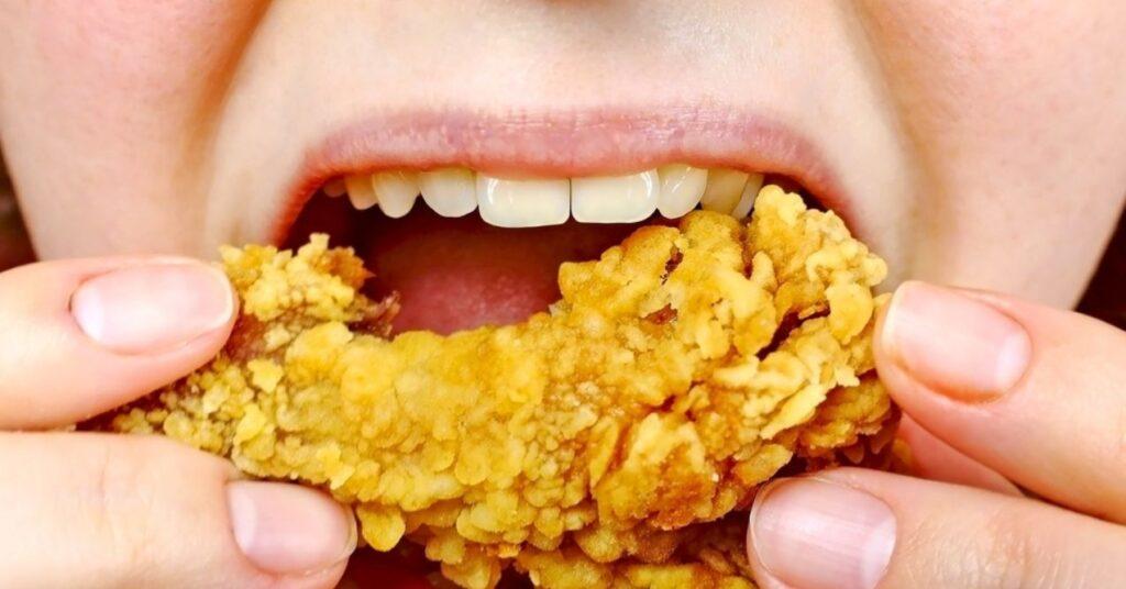 Woman Eating a Takeaway Fried Chicken Wing From Fast Food
