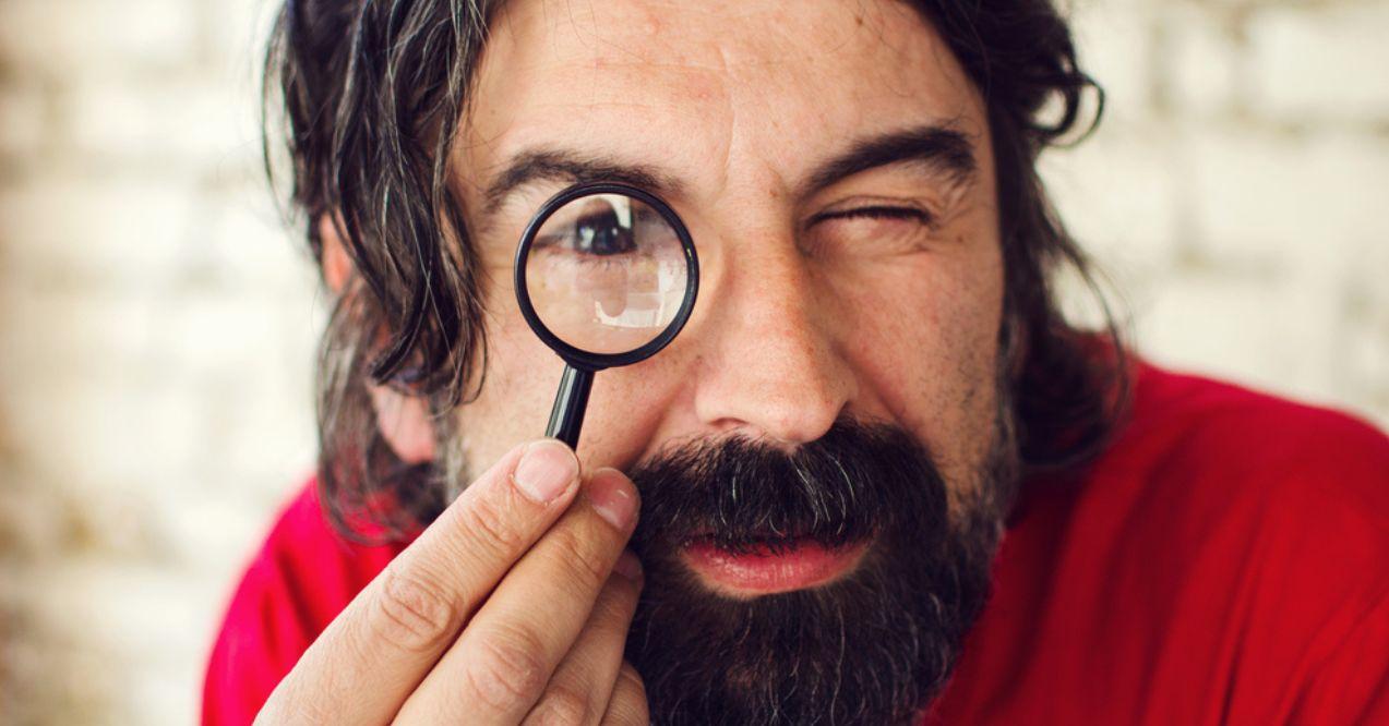Man Holding a Small Magnifying Glass Near His Eye