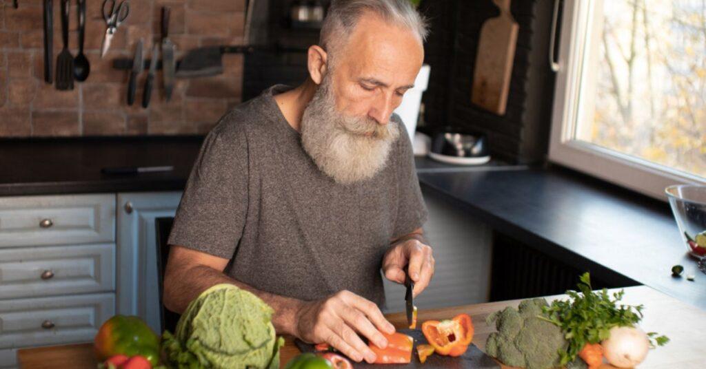Bearded Senior Man Preparing Healthy and Tasty Salad in Kitchen