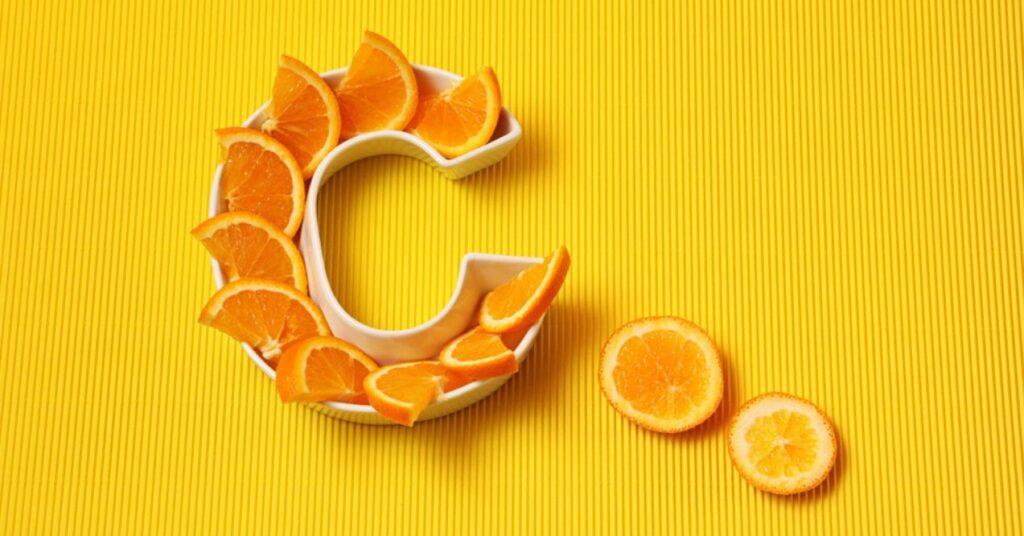 Plate in Shape of Letter C With Orange Slices on Bright Yellow Background