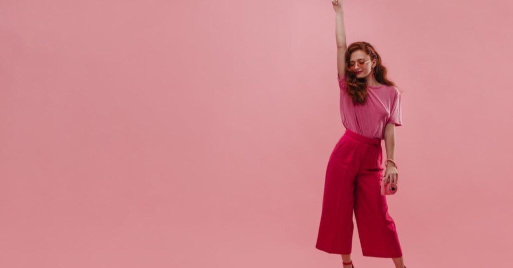 Confident Caucasian Young Lady Raises Hand Straight up While in Photo Studio