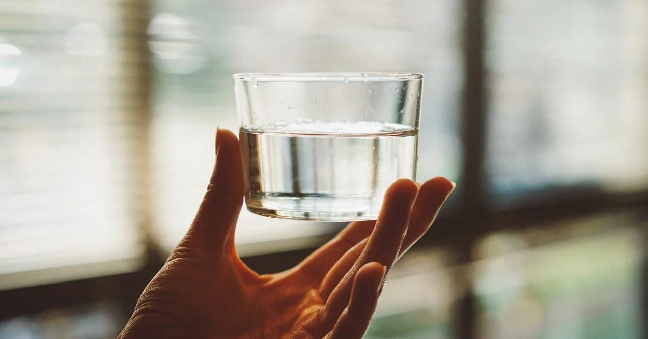 A hand holding a glass of water.
