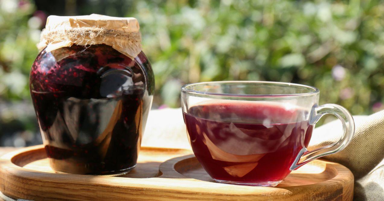Glass cup of tasty elderberry tea and jam. Outdoors.