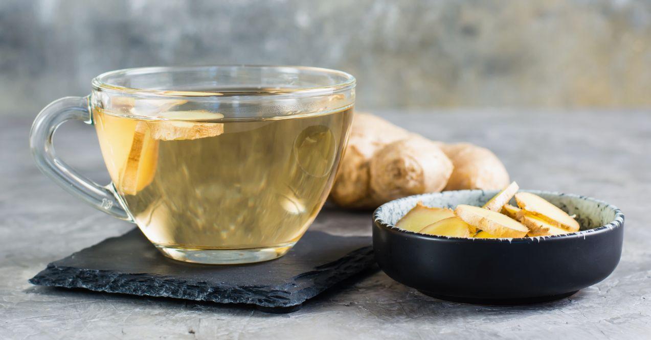 Ginger tea in a cup and chopped root in a bowl on the table. Immune support.