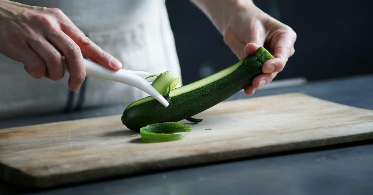 Chef peeling zucchini zoomed in