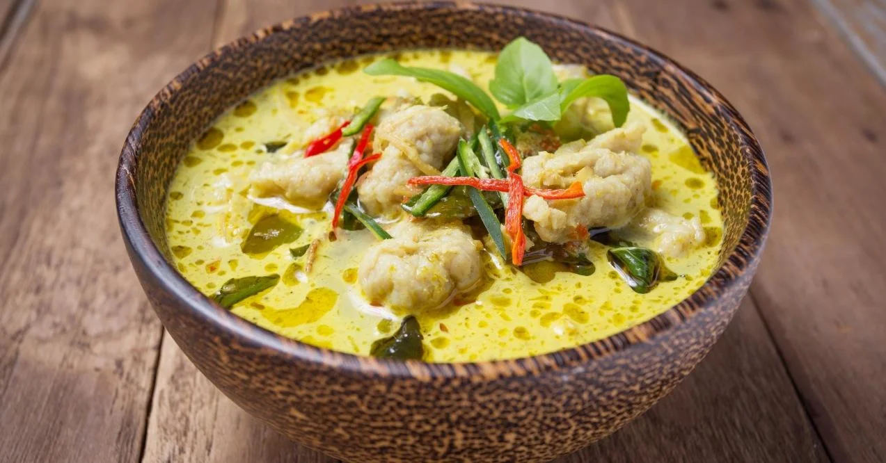 A bowl of green curry with chicken and cilantro zoomed