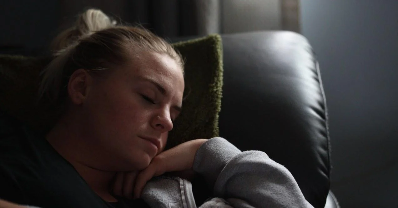A woman napping on a couch. Tired.