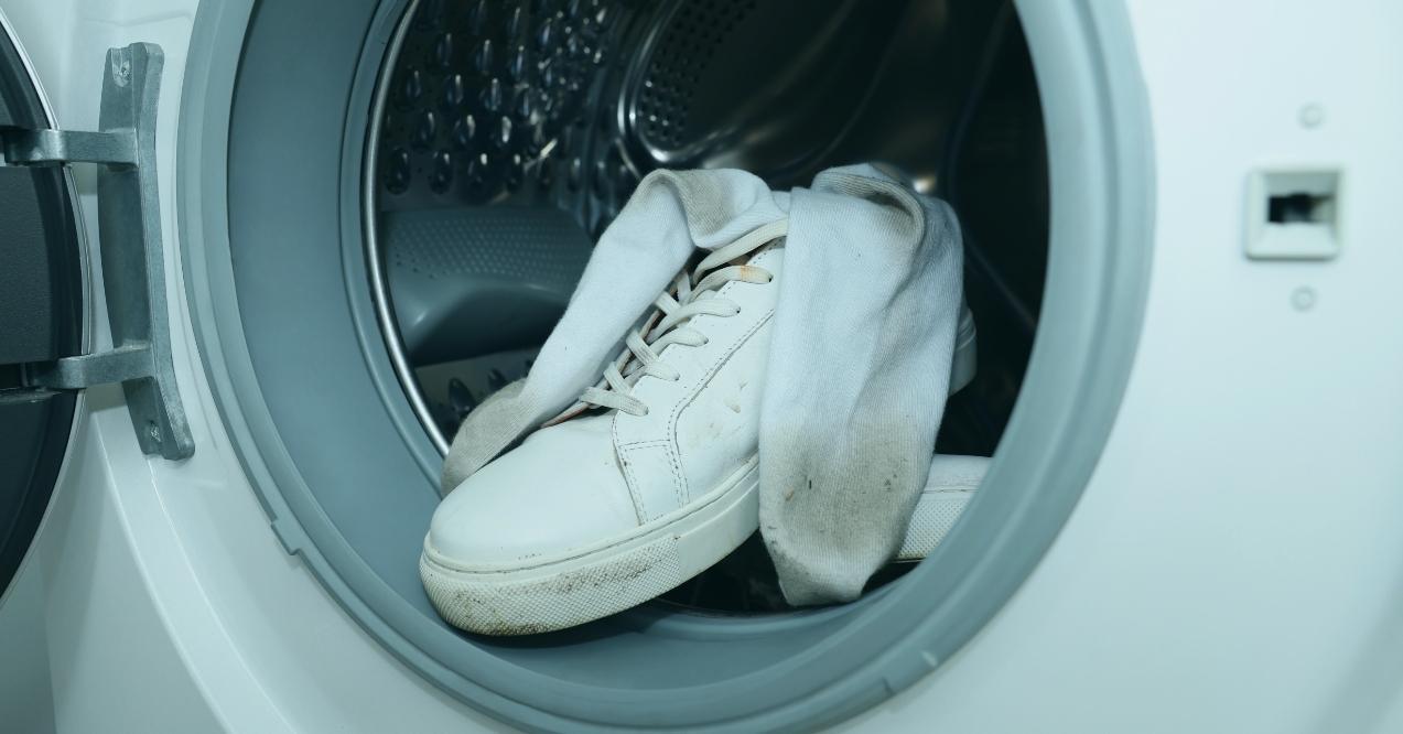 Sneakers with dirty socks in washing machine, closeup