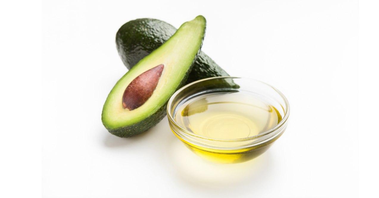 Avocado with some oil in a glass jar in white background