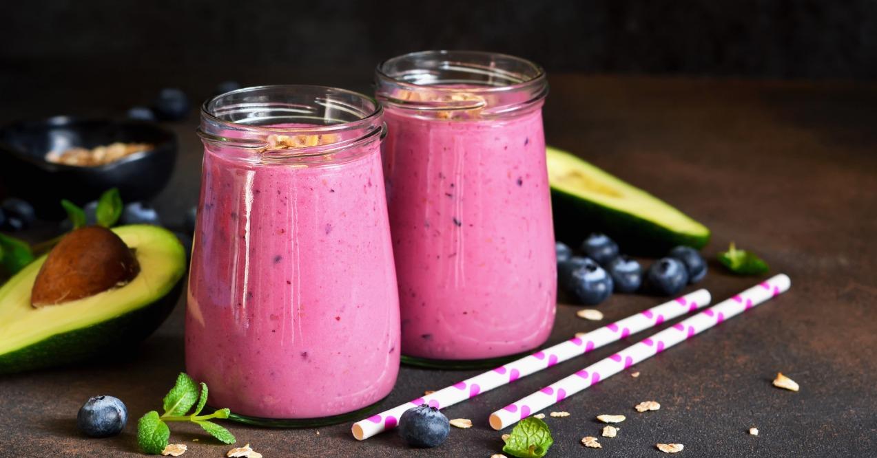 Smoothies of yogurt with avocado, honey, blueberries and granola on a dark background.