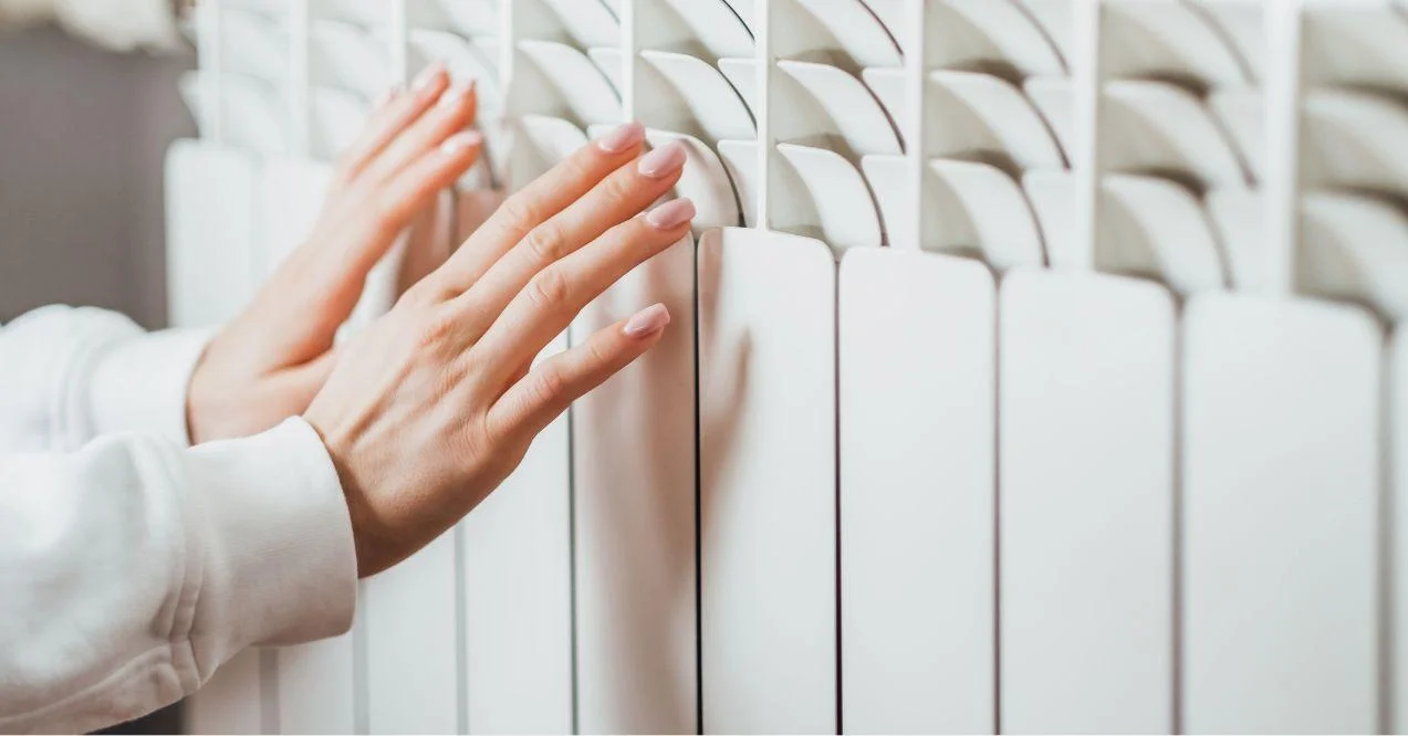 Two hands next to the heater trying to warm up.
