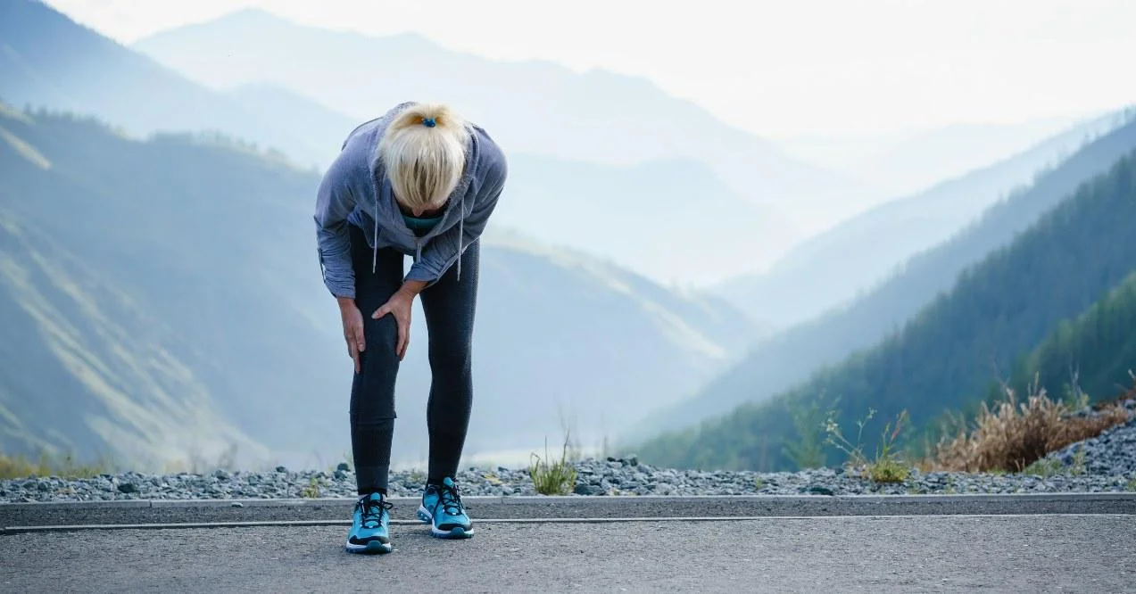 Woman holding her knee out of pain in the nature view/ Stopped running.
