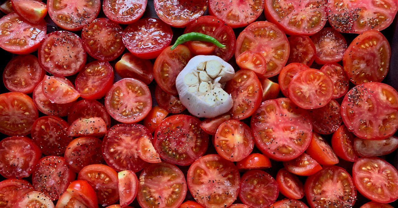 Cut tomatoes on a tray with garlic and chilli cut and before cooking.