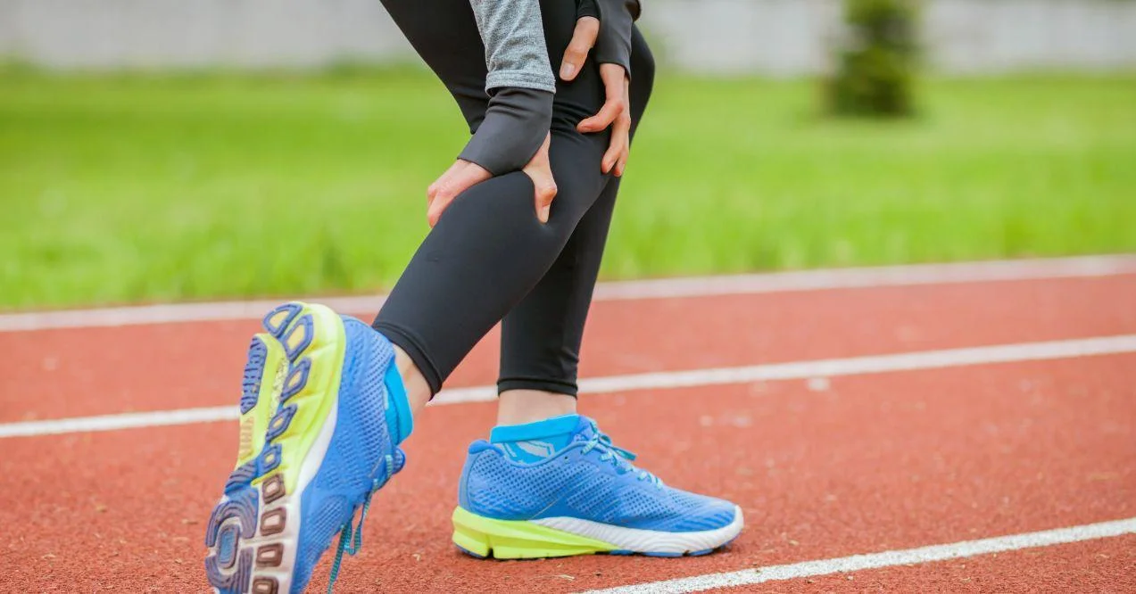 Athlete squeezing her leg due to muscle cramps. Zoomed in.