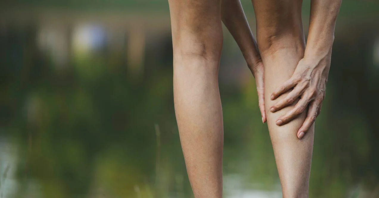 A woman holding her leg due to pain or restless led syndrome.