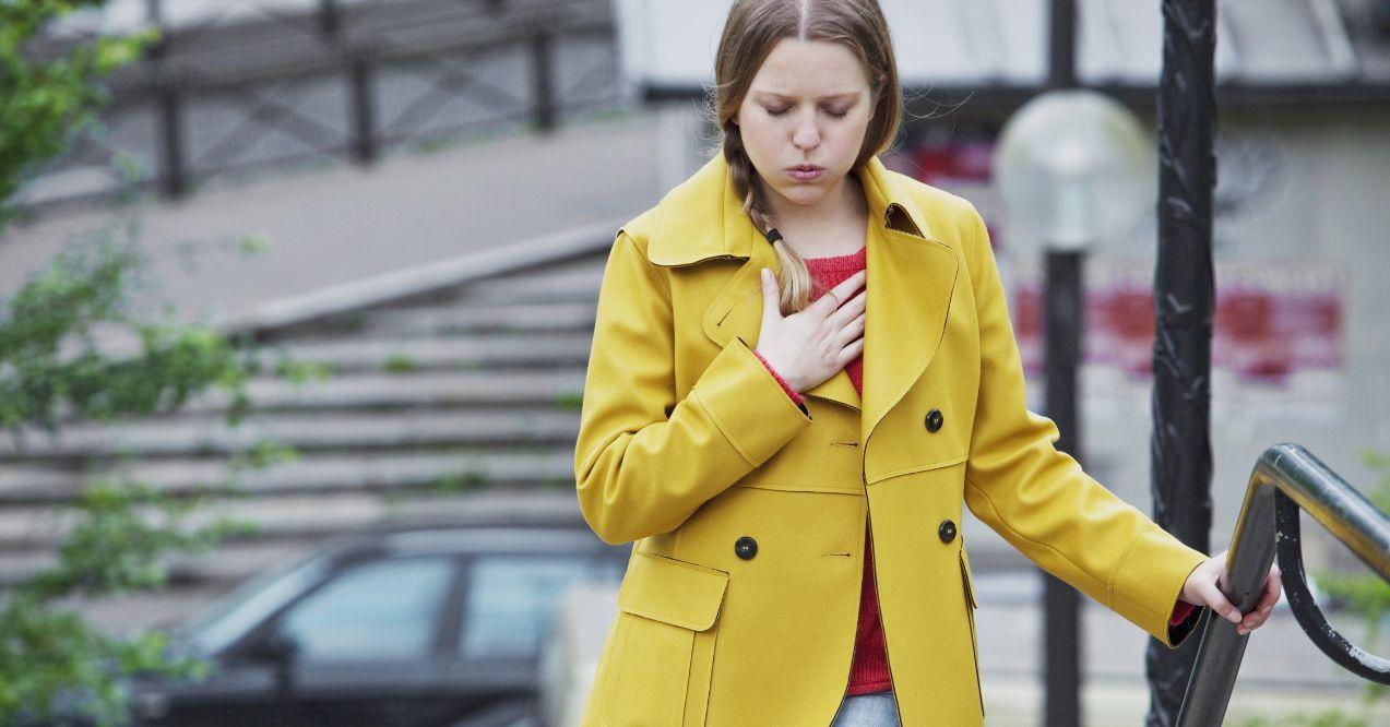 A woman with yellow coat is having difficulty breathing.