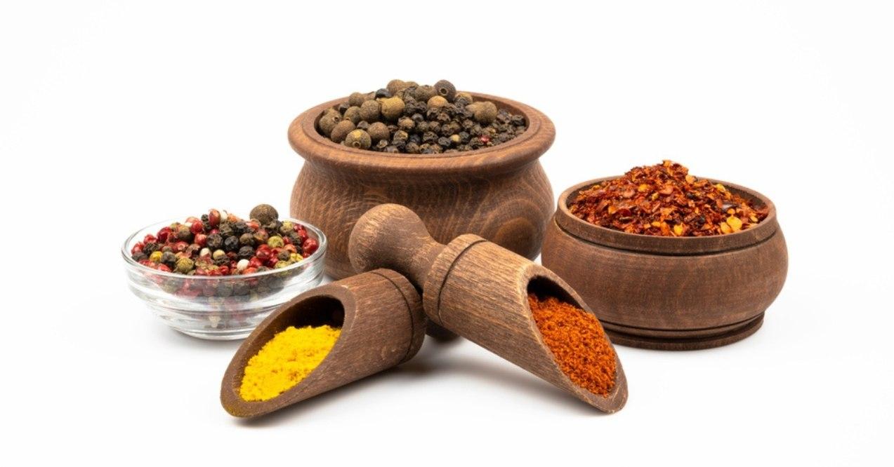 A variety of spice bowls with spices in white background