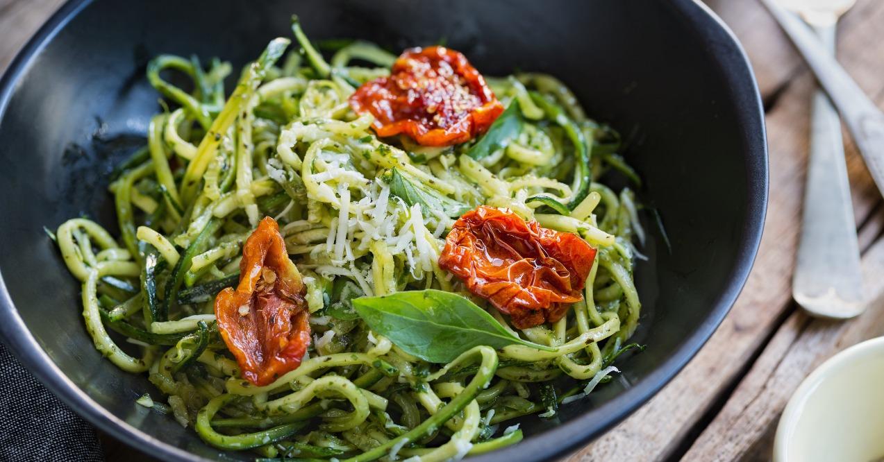 Zucchini pasta in pesto sauce with tomatoes zoomed in
