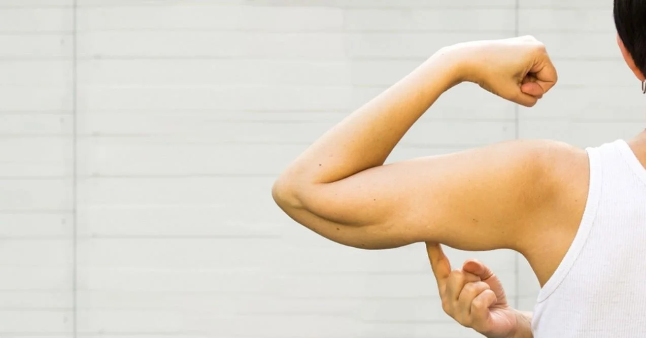 A Faceless Woman Shows the Flabby Muscles of the Arm
