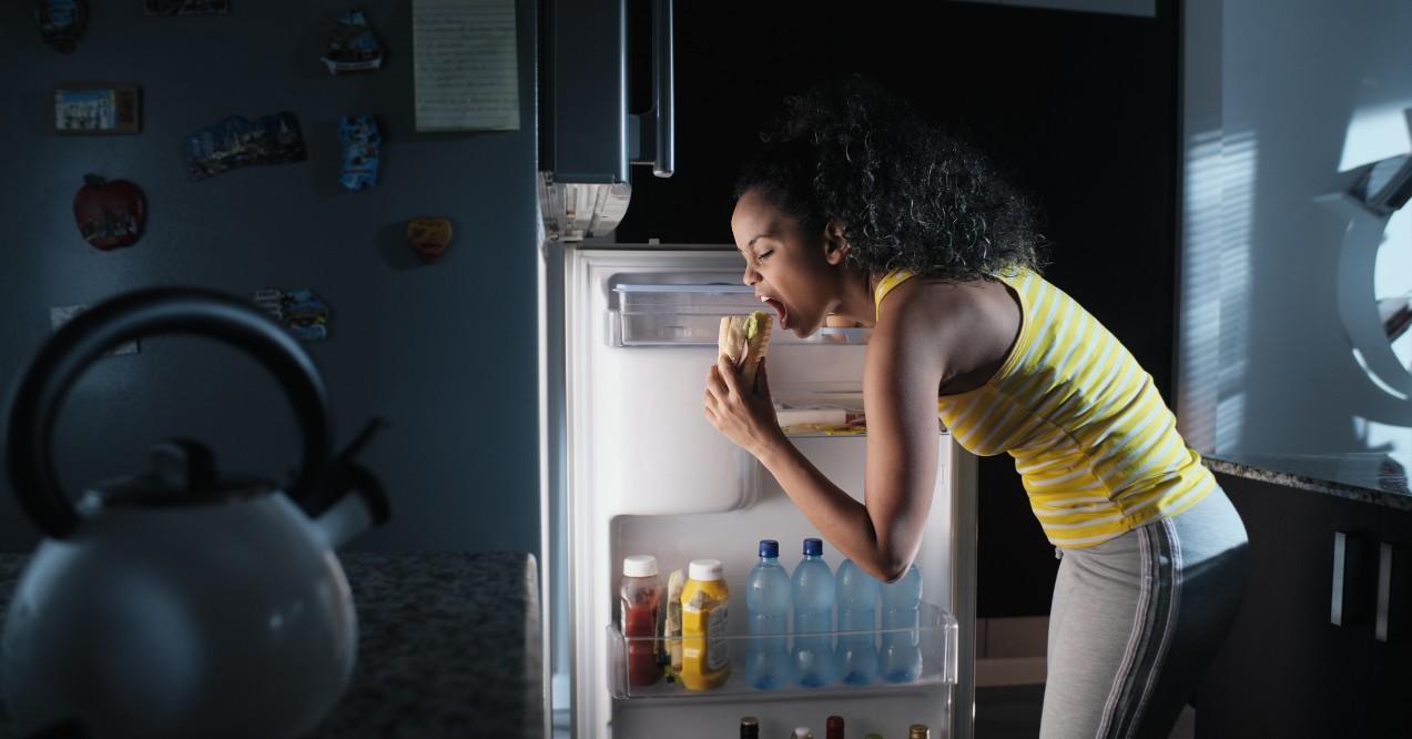 Black Woman Looking Into Fridge for Midnight Snack Due to Hunger