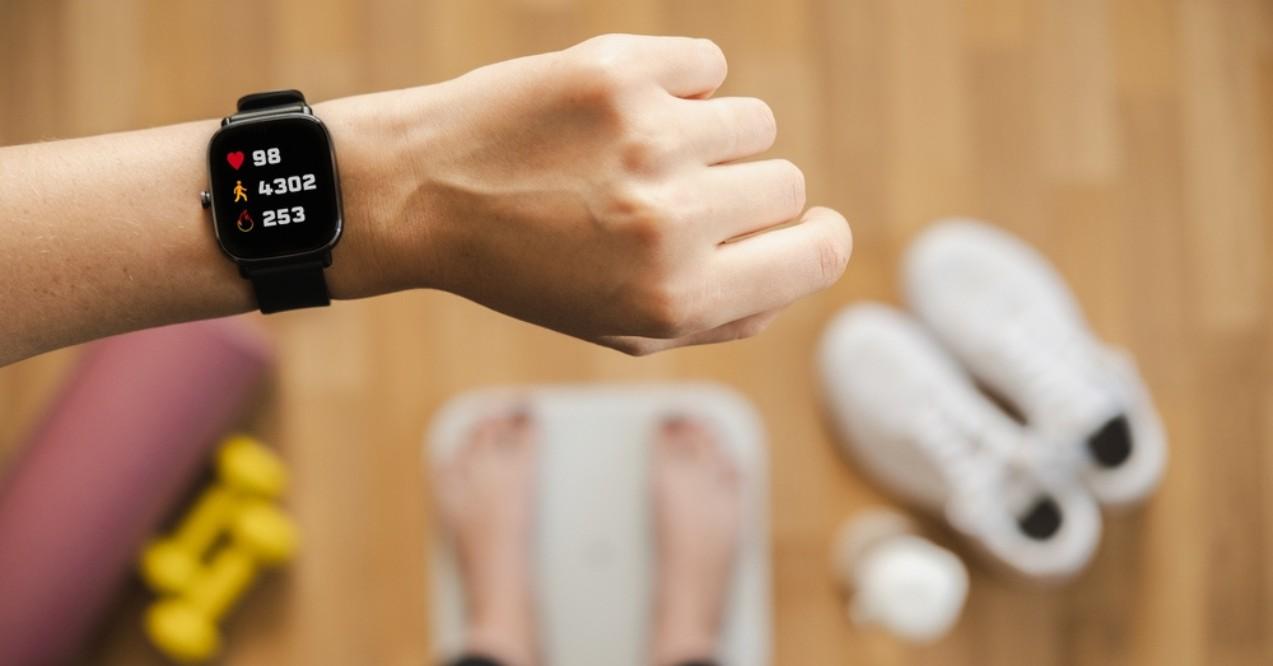 Woman Looking at Fitness Tracker While Standing on Scales