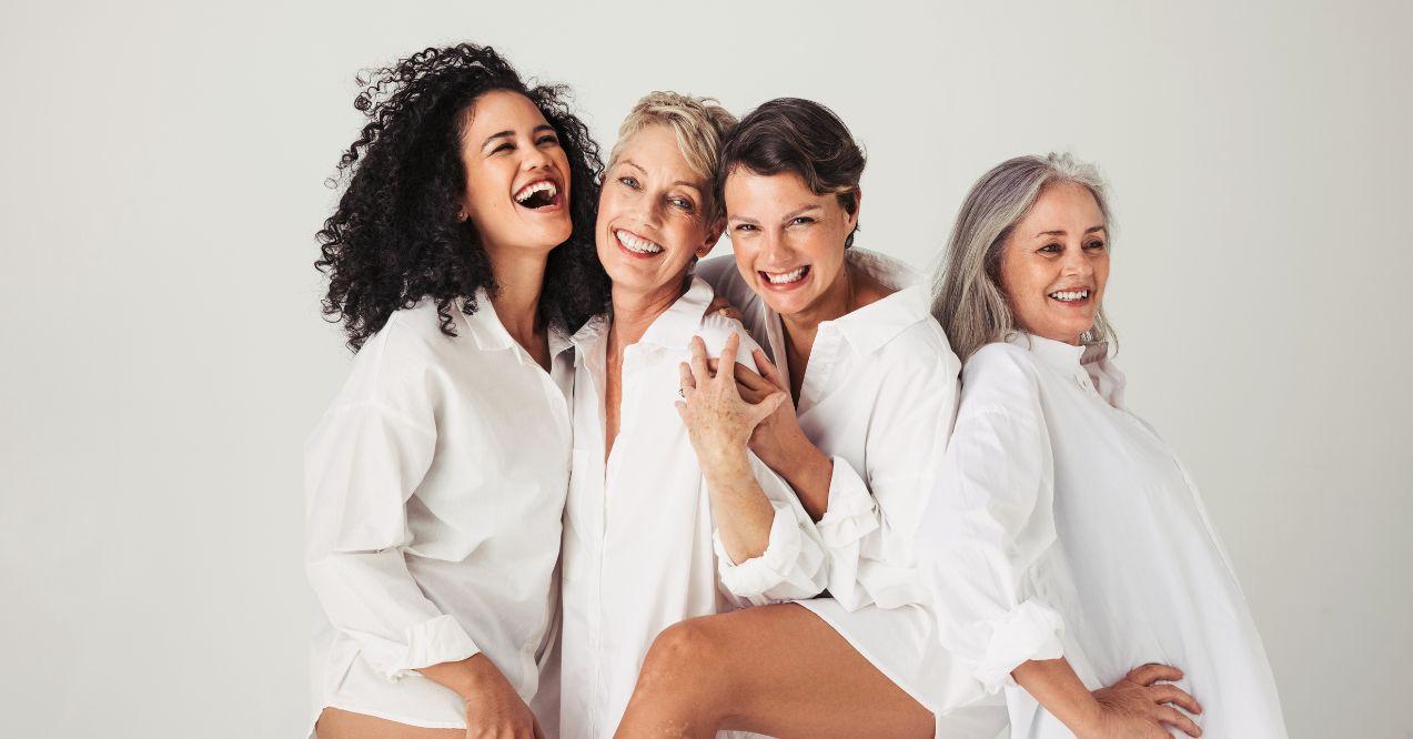 Female models of different ages celebrating their natural bodies in a studio. Four confident and happy women smiling