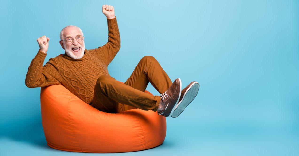 Cheerful bearded grey-haired man sitting in bag chair