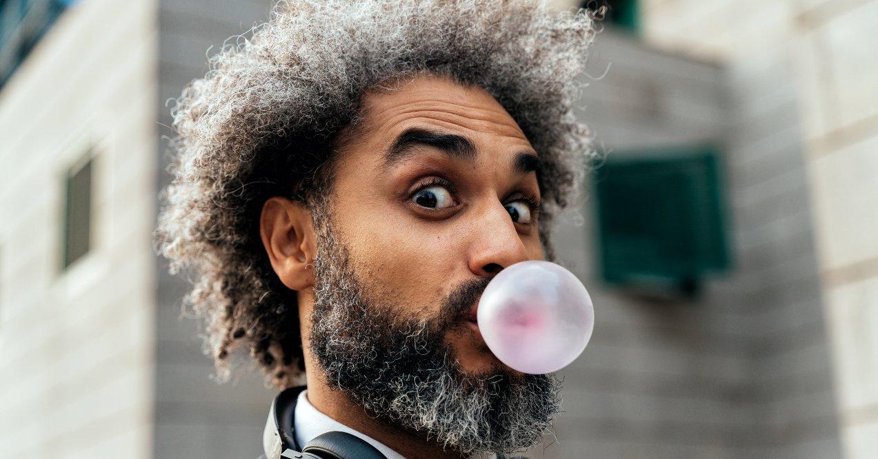 A man chewing bubble gum and blowing balloons 