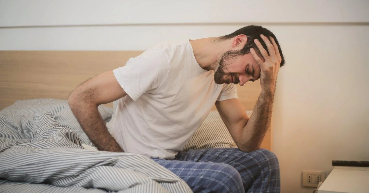 A man is having a fatigue sitting on bed