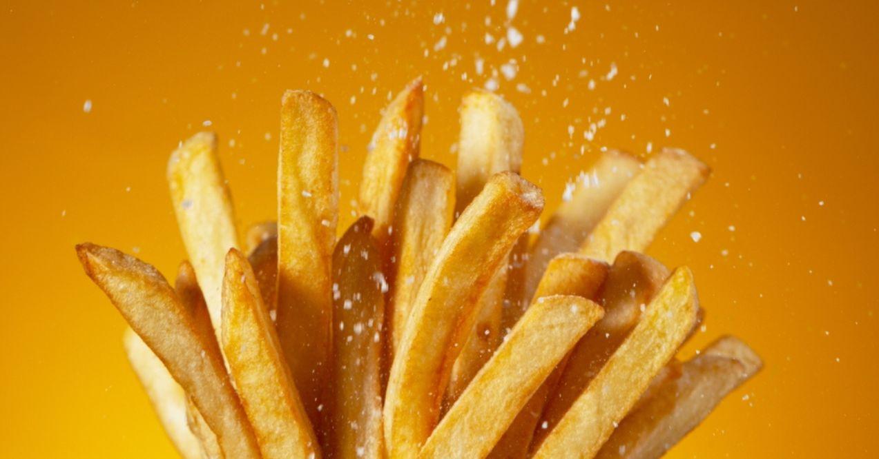 Detail shot of adding salt on French fries