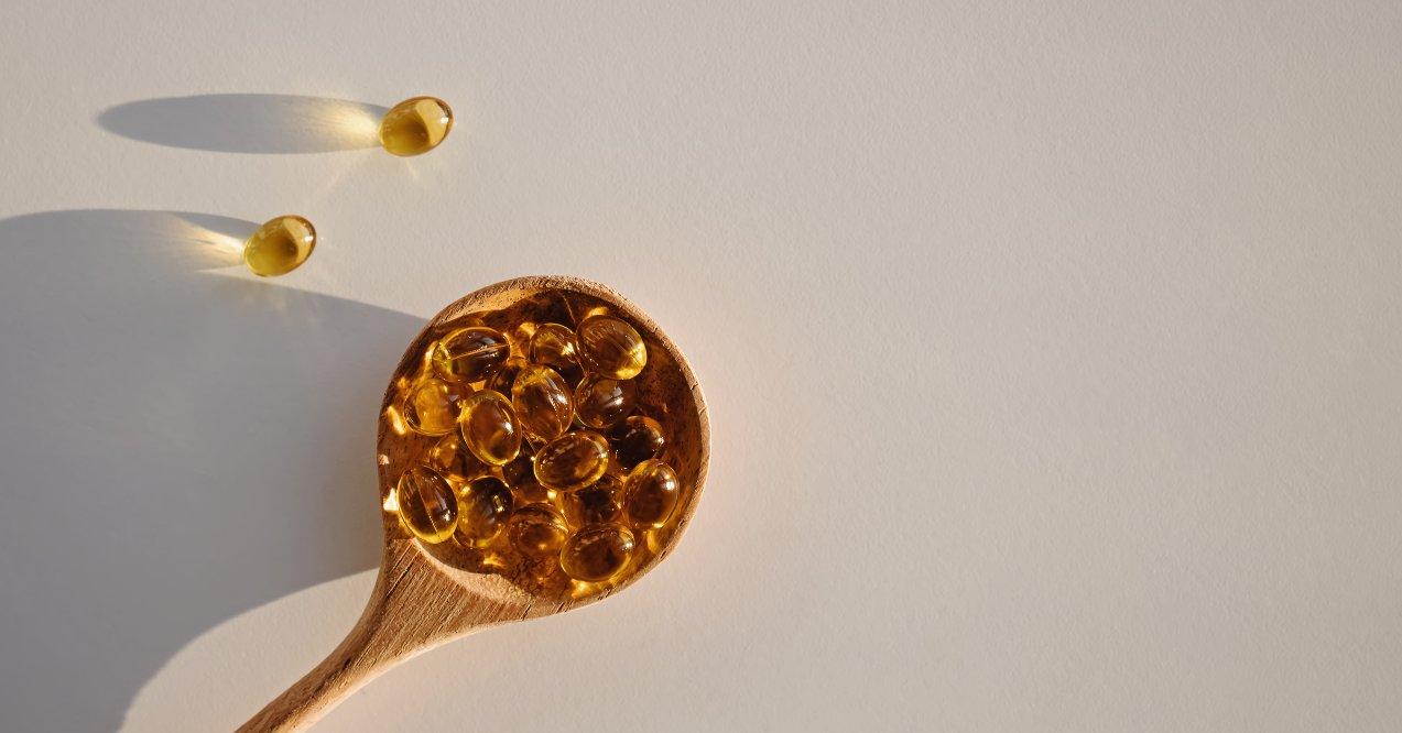 capsules with vitamin d in wooden spoon