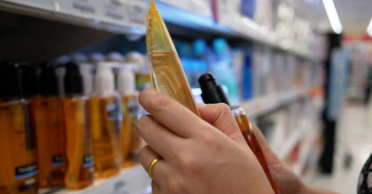 Woman reads ingredients of two hair hygiene products